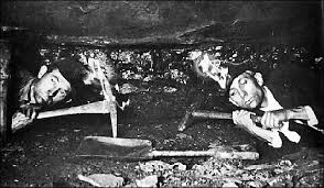 Two miners, flat on their bellies only enough rough for their helmets to touch the ceiling Google Images