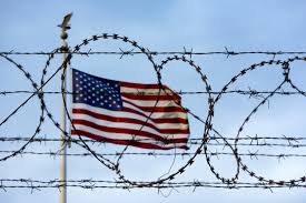 US Flag behind barbed wire Google Images